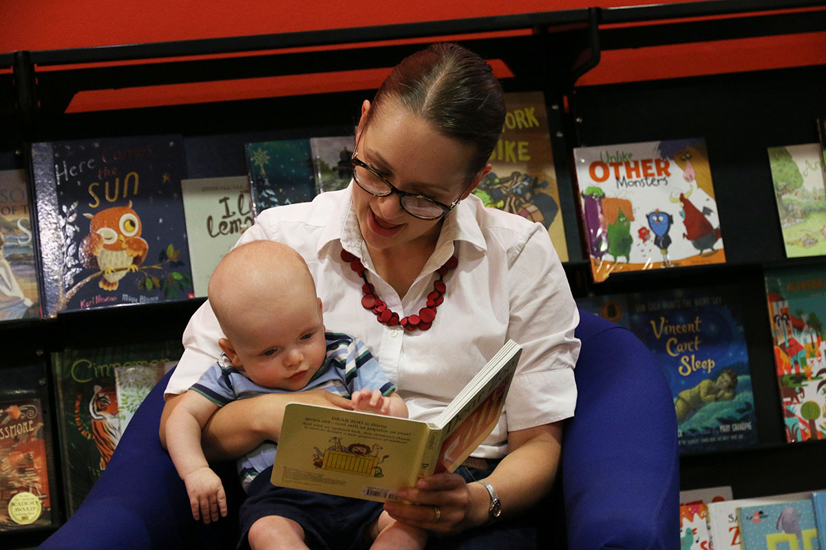 A woman reads to a baby on her lap